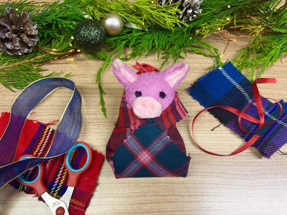 A felt pig decoration and surrounded by fabric and craft scissors