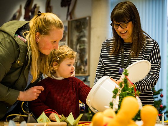 A mother and child take part in a festive crafts session with a member of museum staff