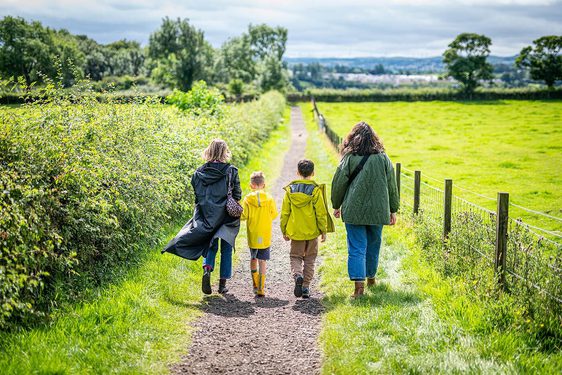A family walking along a countryside path on a sunny day.