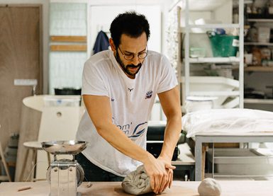A man in a pottery studio moulding clay.