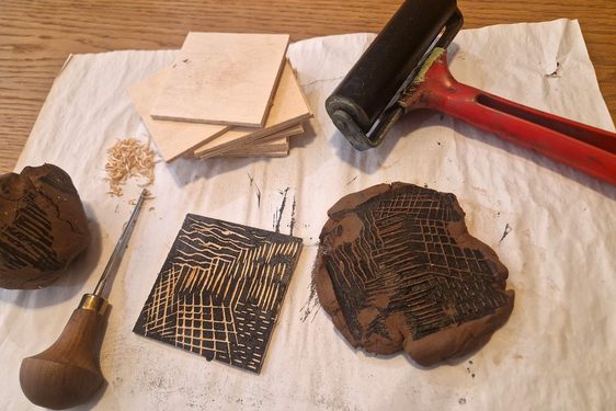 An array of tools for block printing lying on a sheet on a table