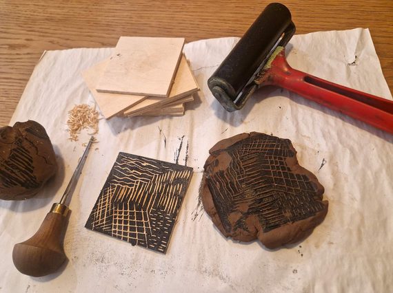 An array of tools for block printing lying on a sheet on a table