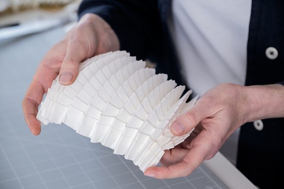 Hands holding a paper folded intricately.