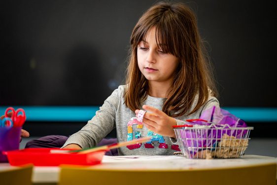 A child sits at a table doing a craft activity