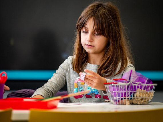 A child sits at a table doing a craft activity