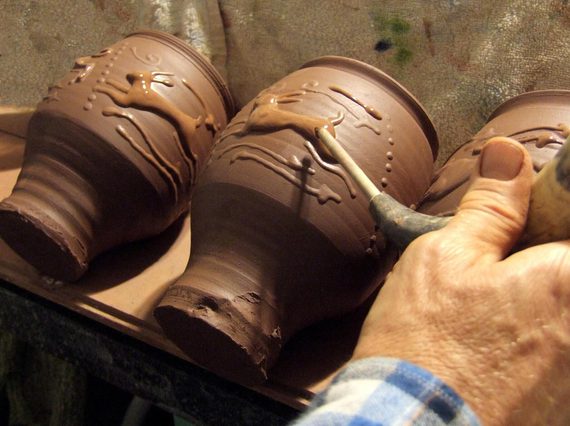 A potter adding finishing touches to a decorated clay pot