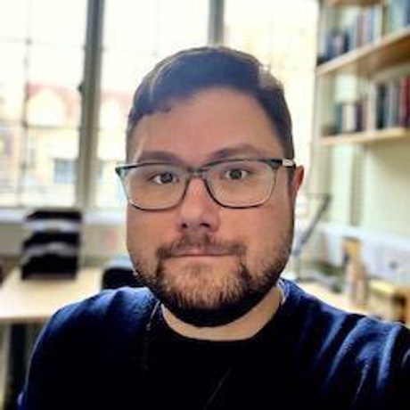 A close up of a man in glasses in an office.