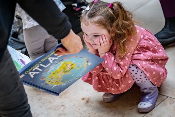 A child sits looking at a picture book.