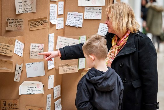 Two people are pointing at some notes written by visitors during a workshop.