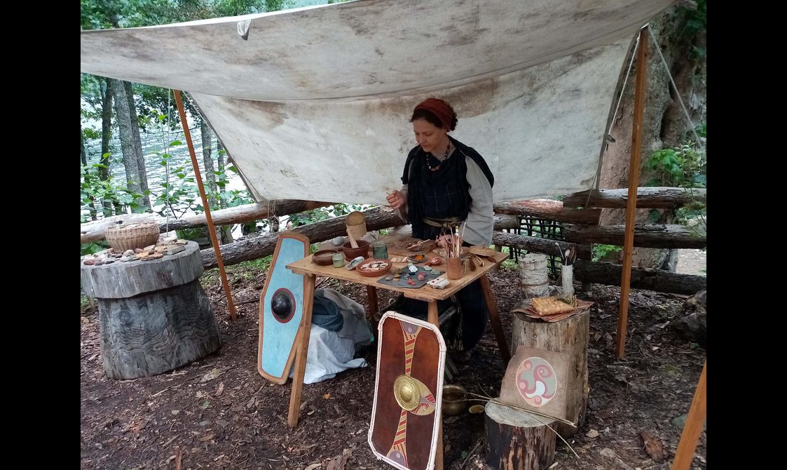 A woman dressed in Pictish clothing stands at a stall