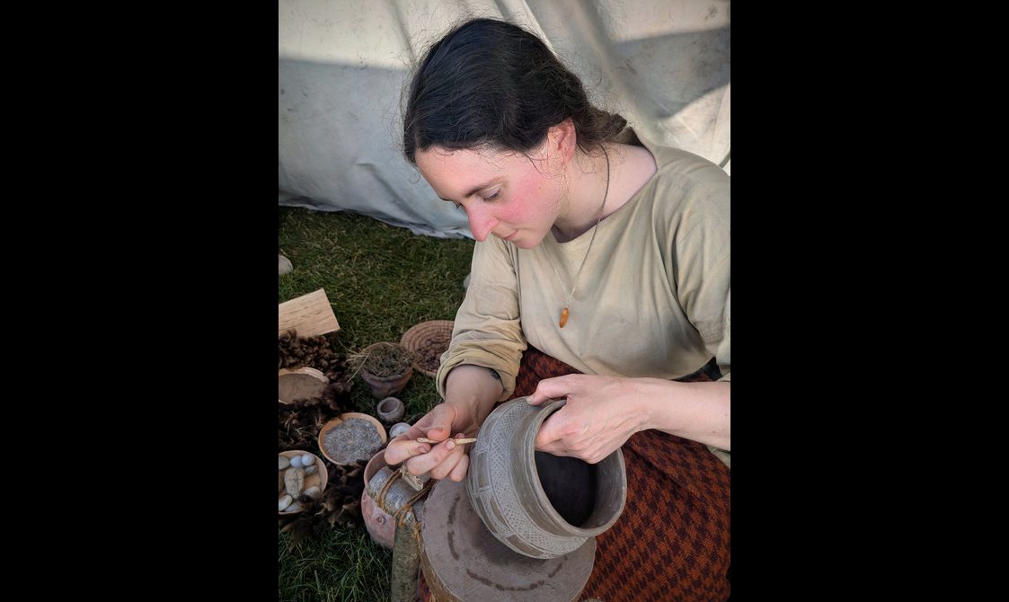 A woman with dark hair holds a pot.