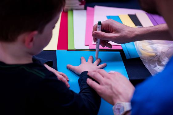 A person tracing a child's hand on a piece of paper.