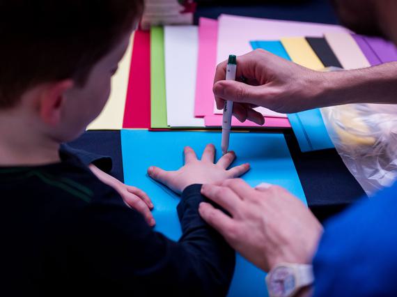 A person tracing a child's hand on a piece of paper.
