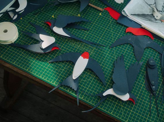 Colourful paper cut outs of swallows on cutting mat