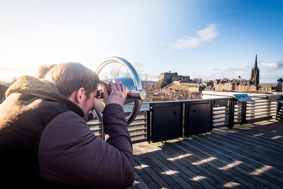 A visitor viewing the landscape of Edinburgh through a tower viewer on the rooftop terrace.