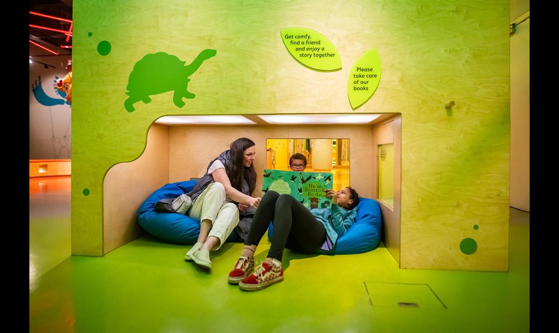 A family sitting on beanbags reading a book in a reading nook.