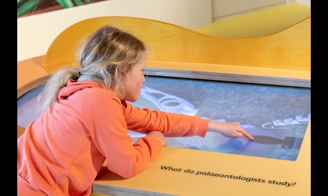 A child playing with a touchscreen in a museum gallery.