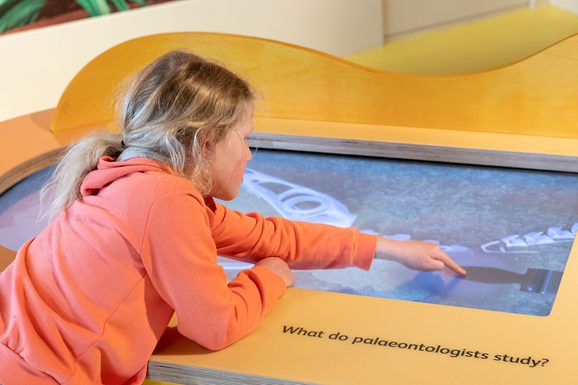 A child playing with a touchscreen in a museum gallery.