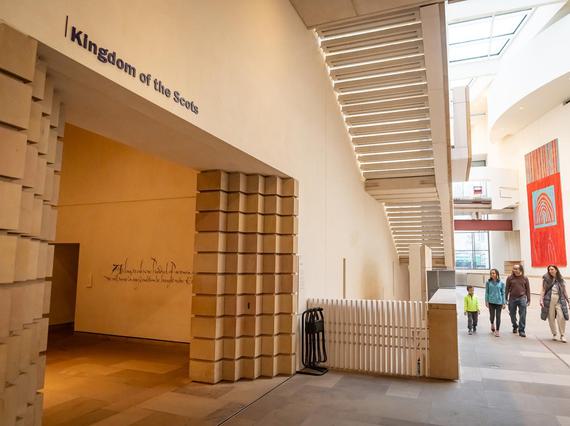 A family walk towards a museum gallery entrance with a sign above that reads, "Kingdom of the Scots."