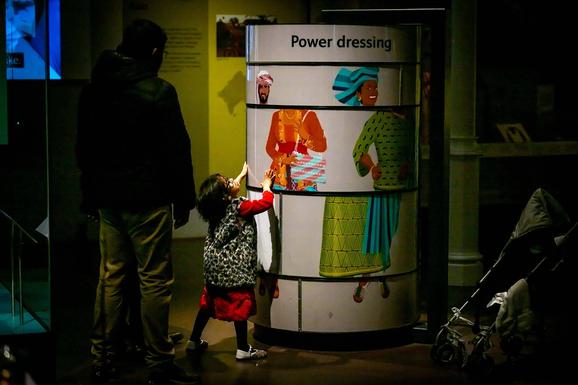 A child interacting with a dressing game in a museum gallery.