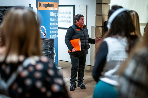 A tour guide gives a tour of a museum to a large group.