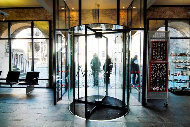 Two people entering a set of revolving doors into a museum.