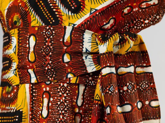 Part of a colourful wax print sundress, with patterns in reds, oranges, yellows, black, and white.