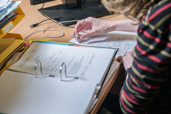 A member of staff organises sheets of paper into a binder.