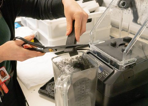 A curator cutting up some Plastazote offcuts into a blender for shredding.