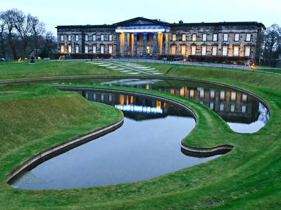 A large museum building overlooking a sculpted garden with sculpted ponds.