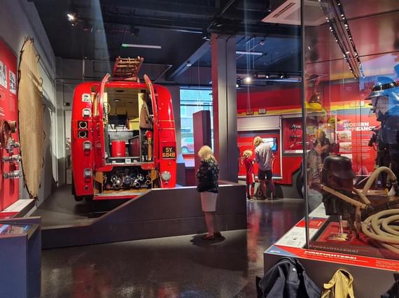 Visitors looking at fire safety items on display in a museum gallery