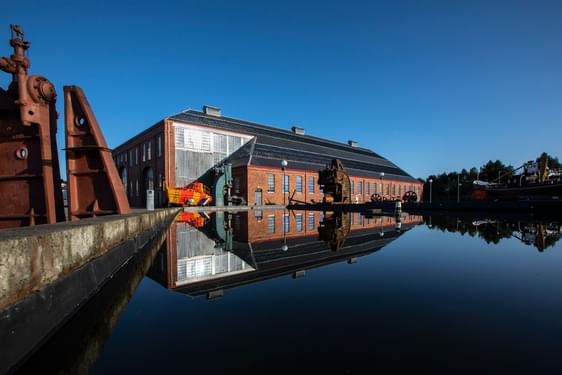 View of a museum building next to a body of water on a sunny day.