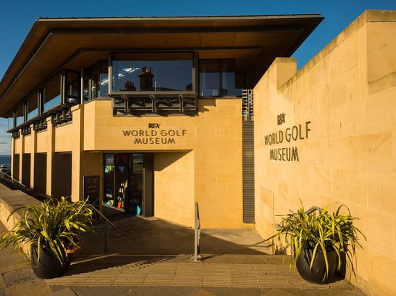 The exterior of a modern museum building constructed of orange-yellow stone, the World Golf Museum.