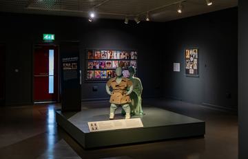 Two mannequins styled with garments on a platform within the exhibition.