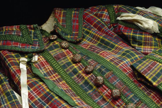 A multicoloured tartan coat with green silk fringing and wooden buttons.