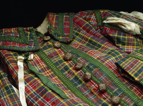 A multicoloured tartan coat with green silk fringing and wooden buttons.