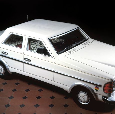 A coffin in the shape of a white Mercedes-Benz car.