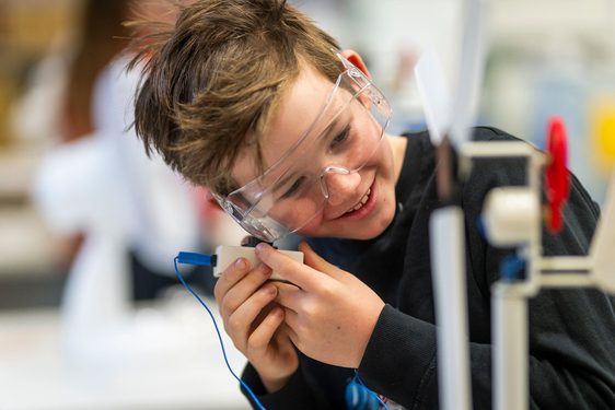 A child wearing goggles and holding a switch for a scientific experiment.