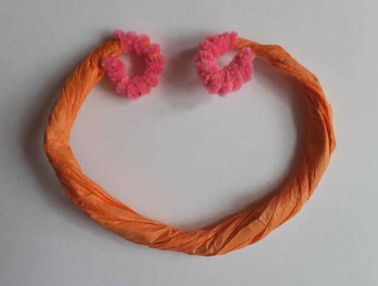 Orange paper twisted into a shape with loops at both ends.