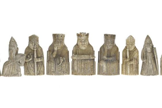 Gold Lewis chess pieces arranged in a row.