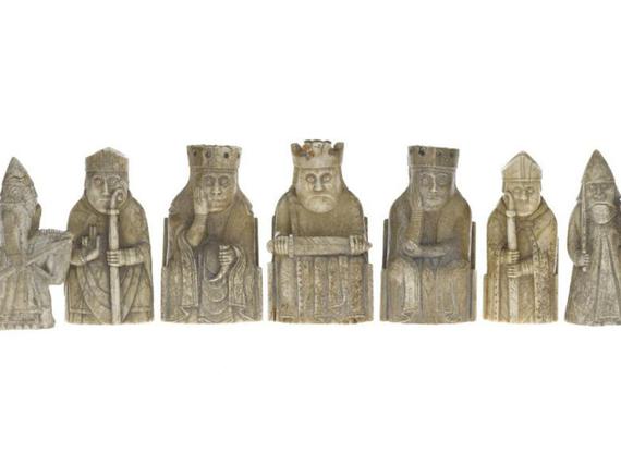 Gold Lewis chess pieces arranged in a row.