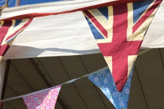 A row of bunting made from United Kingdom flags and other materials, tied to the top of a frame.