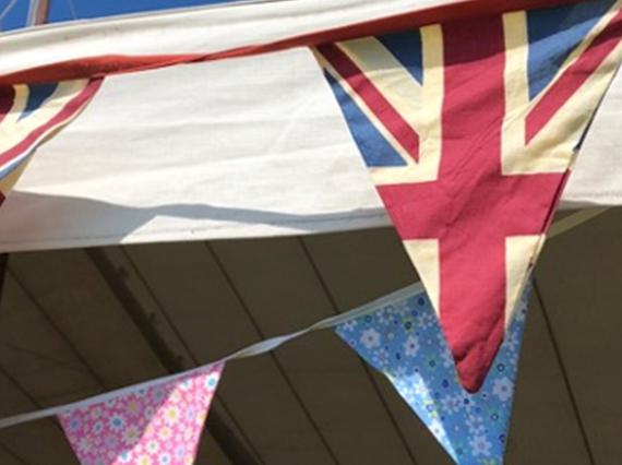 A row of bunting made from United Kingdom flags and other materials, tied to the top of a frame.