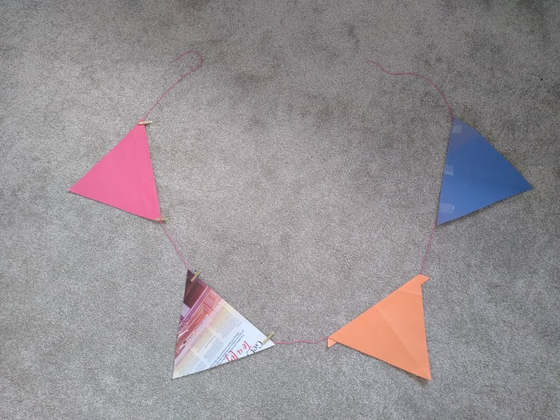 Four buntings in various colours tied to a red string, arranged in a circular pattern.