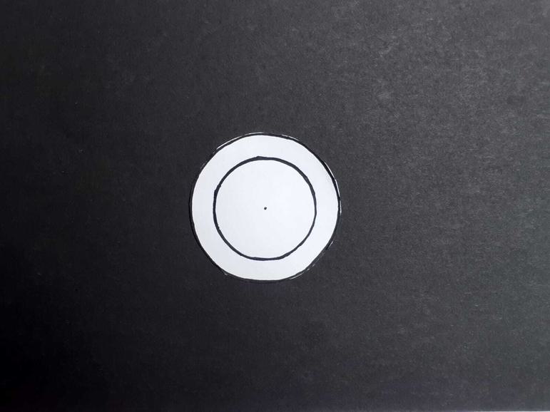 A paper circle with two drawn circles: one outer and one inner.