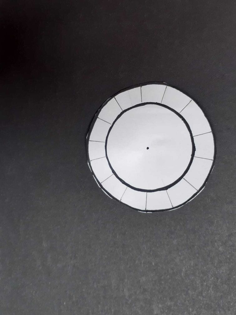 A paper circle with two drawn circles and 1.5 cm lines drawn on the outer circle.