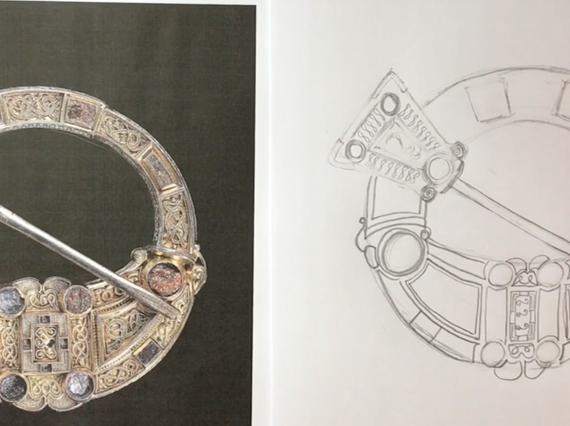 A hand holding a pencil, sketching the Hunterston brooch.