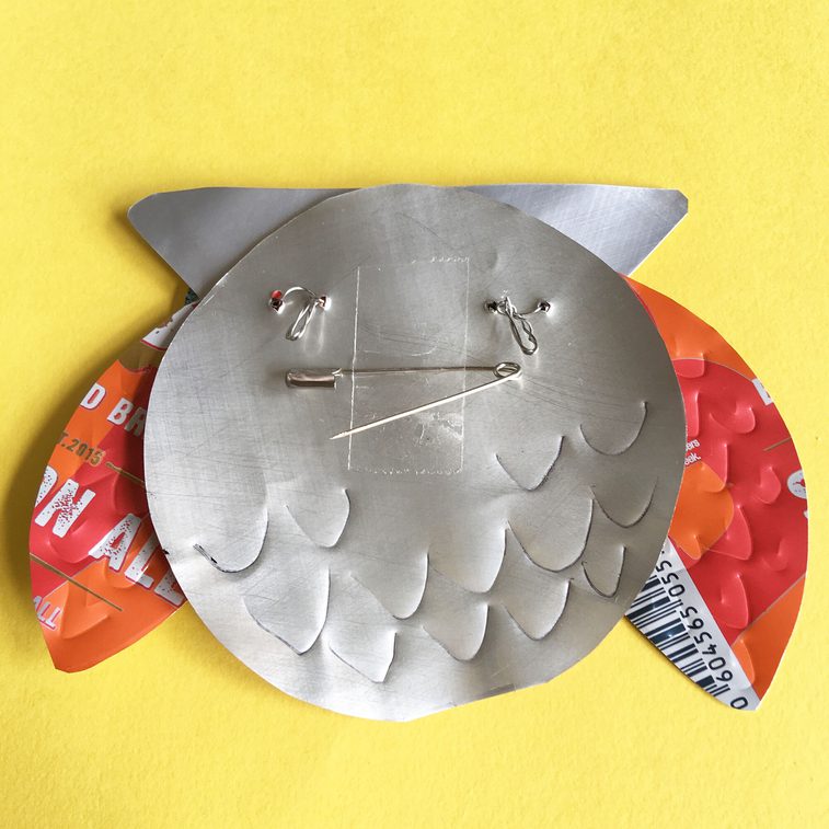 A stylish owl badge crafted from a fizzy drink can.