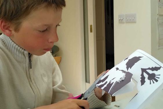 A boy using scissors to cut paper art.