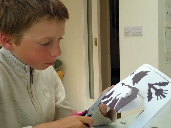 A boy using scissors to cut paper art.